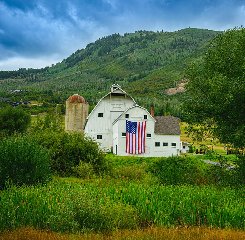 Classic Landmark Farmhouse with dramatic stormy clouds rising behind the Wasatch Mountain Range in the Historic Park City, Utah, USA