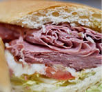 Bright close up of authentic New England style “grinder" Italian cold cut sandwich filled with meat cheese and lettuce and tomato.