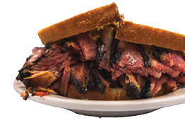 Famous thick cut pastrami sandwhich in New York City at a deli with great meet great cuts on rye bread with oils dripping at a diner while hand held and half cut for easy eating