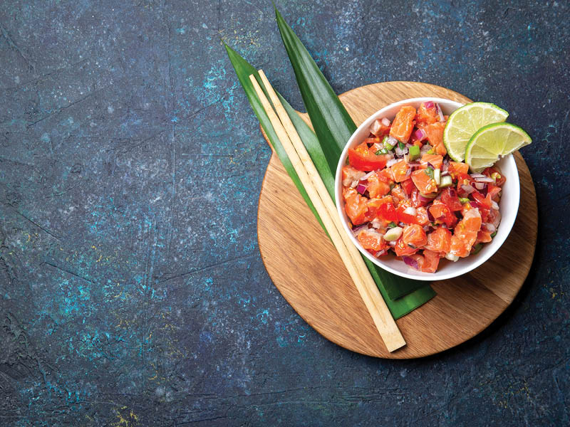 Lomi lomi salmon, hawaiian raw salmon salad on blue background