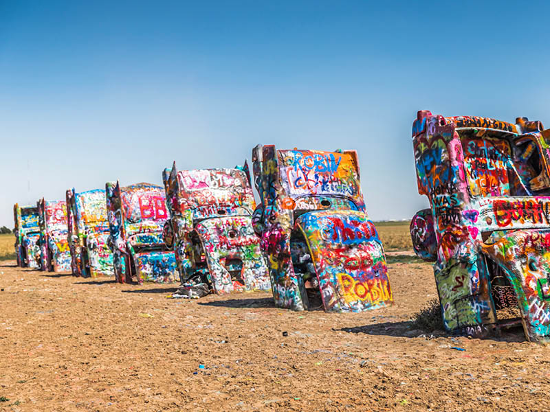 Amarillo, Texas / USA - July 24, 2019: Cadillac Ranch, located along I-40, is a public art sculpture of antique Cadillacs buried nose-down in a field.