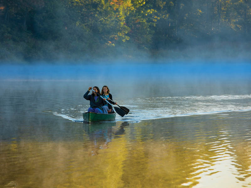 Mother and daughter canoeing in morning mist