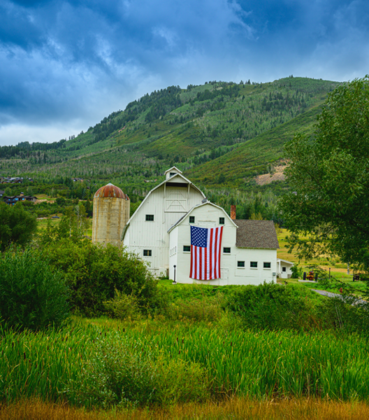 Classic Landmark Farmhouse with dramatic stormy clouds rising behind the Wasatch Mountain Range in the Historic Park City, Utah, USA