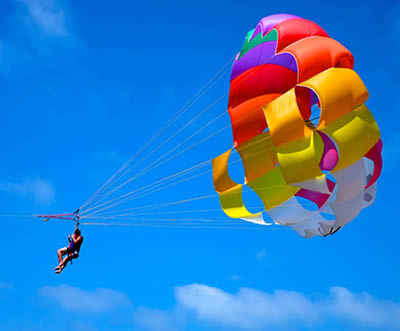 A parachute being towed at sea with a clear blue sky in the background.