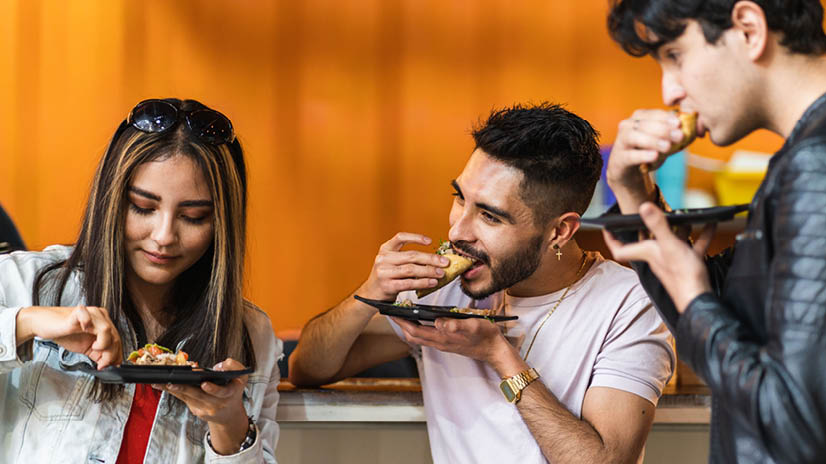 group of friends dining tacos at night in a street business