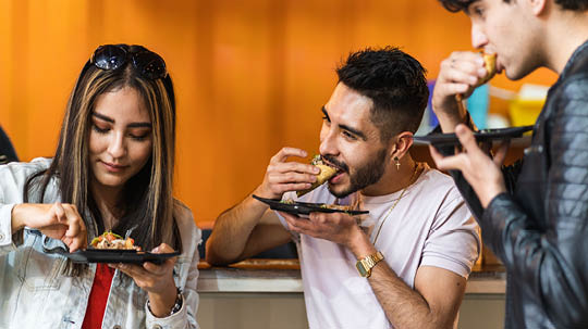 group of friends dining tacos at night in a street business