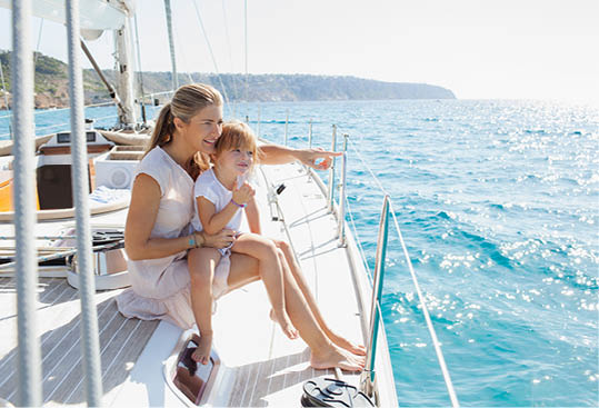 Beautiful mother and daughter child together on private luxury sailing yacht, pointing smiling outdoors. Family activities summer vacation at sea, travel transportation leisure recreation lifestyle.
