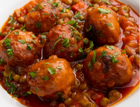 Veal meatballs in sauce with peas and tomato. Traditional Basque country tapas in the north of Spain.