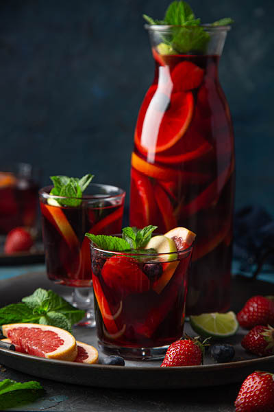glass of homemade red wine sangria with fruits and berries, selective focus, dark background