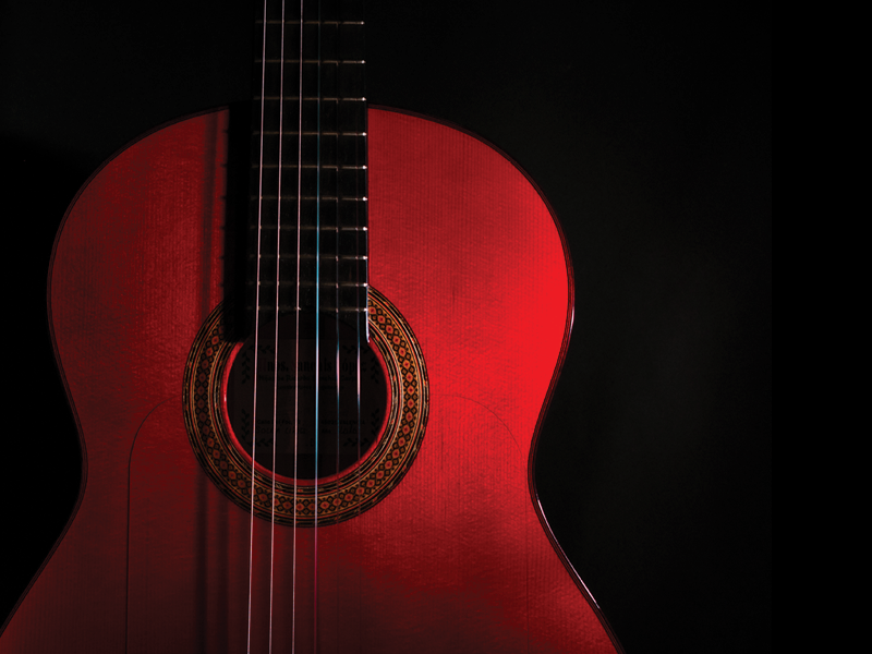 spanish classical red guitar close-up on a black background