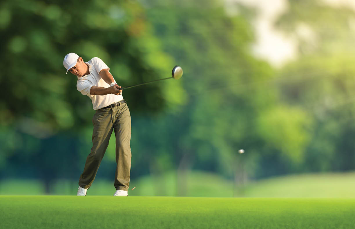 Golfer hitting golf ball with driver.