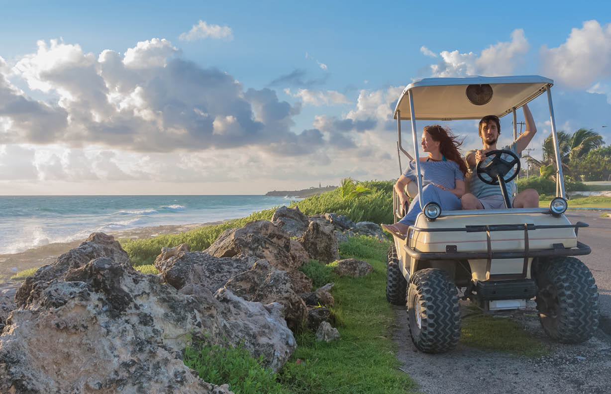 couple driving a golf cart at tropical beach on Isla Mujeres, Mexico
