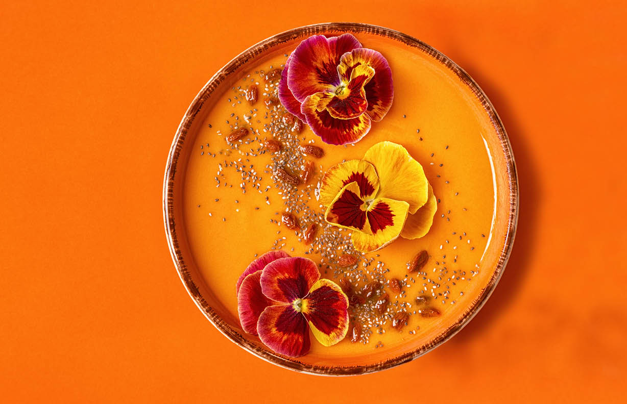 Smoothie bowl with edible pansy flowers, chia seeds, goji berries, top view.