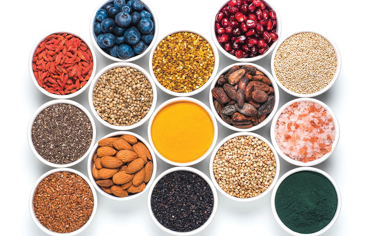 Various superfoods in smal bowl isolated on white background. Superfood as chia, spirulina, raw cocoa bean, goji, hemp, quinoa, bee pollen, black sesame, turmeric. Top view or flat-lay.