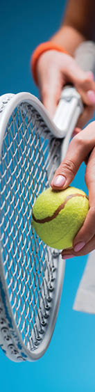 cropped view of sportive young woman holding tennis racket and ball while playing on blue