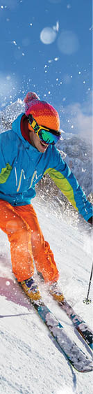 A skier skiing downhill a groomed alpine slope during sunny winter day