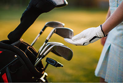 A gloved hand near a golf club. Golf equipment.
