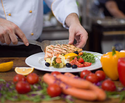 cook chef decorating garnishing prepared meal dish on the plate in restaurant commercial kitchen