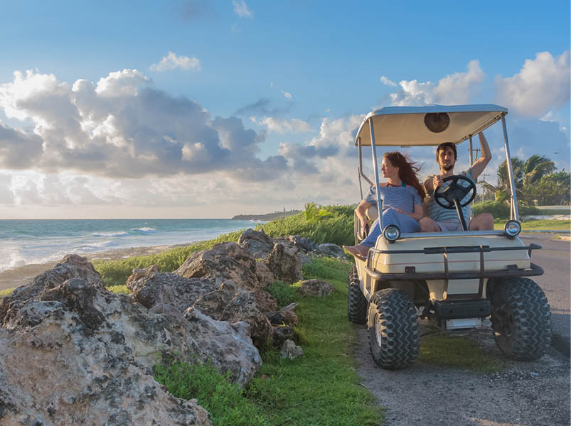 couple driving a golf cart at tropical beach on Isla Mujeres, Mexico