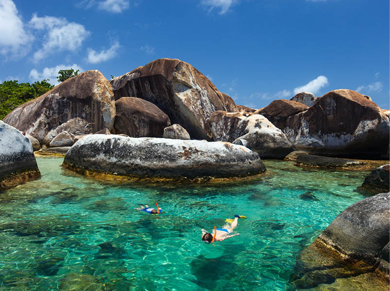 Family of mother and son snorkeling in turquoise tropical water among huge granite boulders at The Baths beach area major tourist attraction on Virgin Gorda, British Virgin Islands, Caribbean