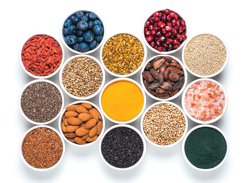 Various superfoods in smal bowl isolated on white background. Superfood as chia, spirulina, raw cocoa bean, goji, hemp, quinoa, bee pollen, black sesame, turmeric. Top view or flat-lay.