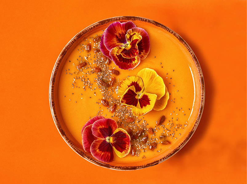 Smoothie bowl with edible pansy flowers, chia seeds, goji berries, top view.