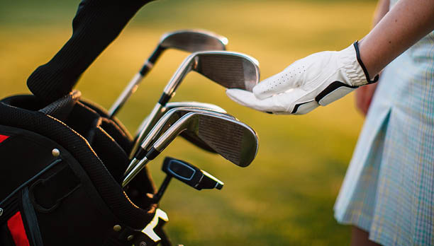A gloved hand near a golf club. Golf equipment.