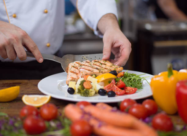 cook chef decorating garnishing prepared meal dish on the plate in restaurant commercial kitchen