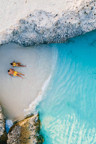 a couple of men and women on the beach of Tres Trap Aruba Caribbean Island. Tres Trapi Bay is popular with locals for snorkeling and diving in the turqouse colored ocean