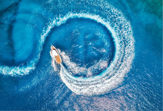 Aerial view of the speed boat in clear blue water at sunset in summer. Top view from drone of fast floating yacht in mediterranean sea. Travel in Oludeniz, Turkey. Tropical landscape with motorboat