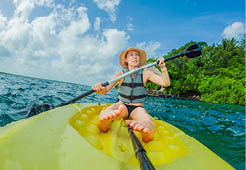 Unaltered woman tourist kayaking on the serene turquoise waters of Lake Bacalar, Mexico, surrounded by natural beauty. Adventure, relaxation, and outdoor travel concept in a peaceful tropical