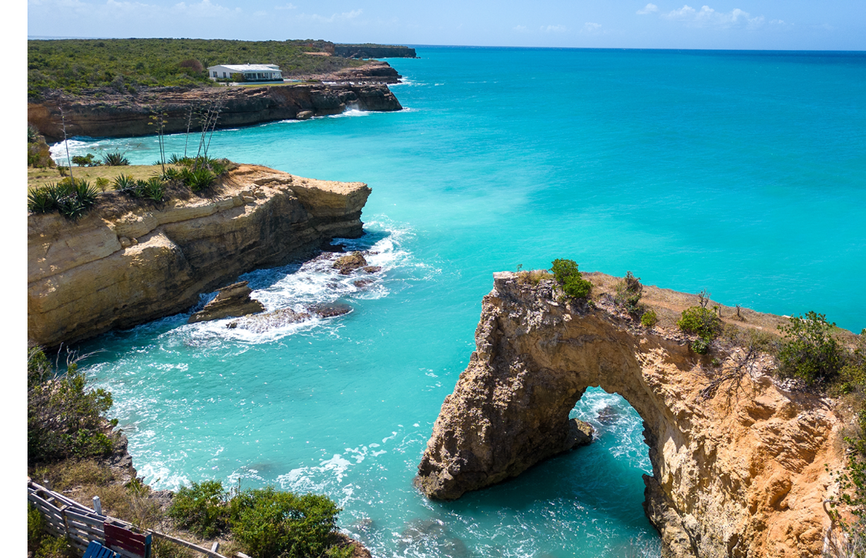 Anguilla Arch. Natural hole carved in the rock. Turquoise sea on a beautiful sunny day in the Caribbean.