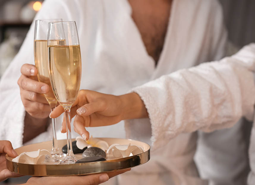 Young couple taking glasses of champagne in spa salon, closeup