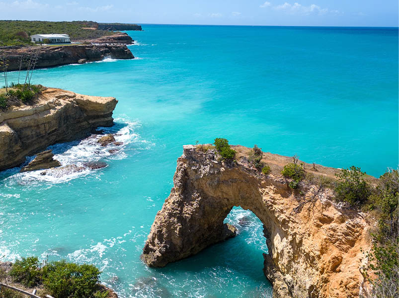 Anguilla Arch. Natural hole carved in the rock. Turquoise sea on a beautiful sunny day in the Caribbean.