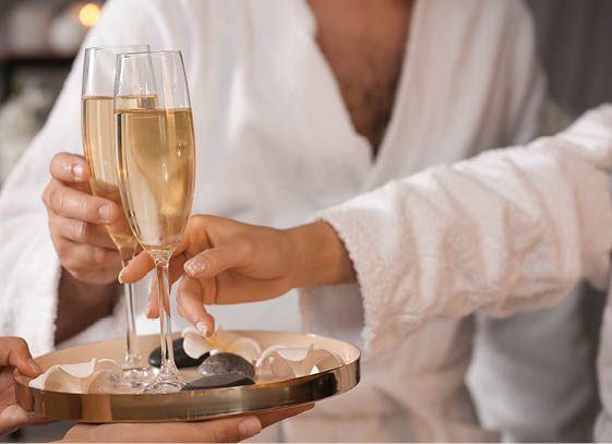 Young couple taking glasses of champagne in spa salon, closeup