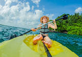 Unaltered woman tourist kayaking on the serene turquoise waters of Lake Bacalar, Mexico, surrounded by natural beauty. Adventure, relaxation, and outdoor travel concept in a peaceful tropical