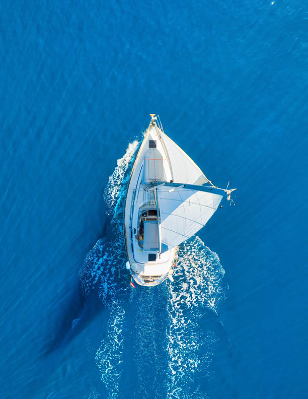 Wave and sail yacht on the sea as a background. Sea and waves from top view. Blue water background from top view. Top view from drone. Summertime vacation. Travel image
