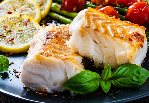 Fish dish - fried cod fillet with asparagus on wooden table 