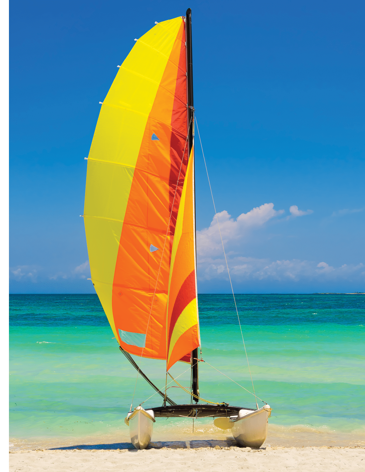 Catamaran with its colorful sails wide open landed on the famous Varadero beach in Cuba