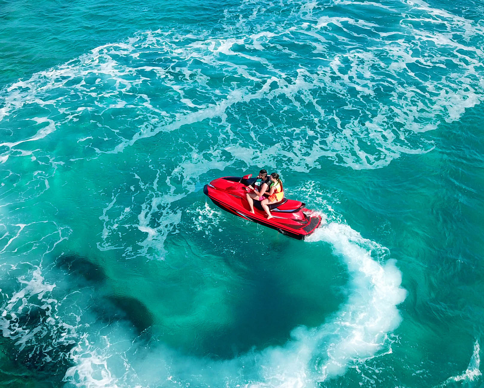 Aerial photo of jet ski with couple cruising in low speed in Caribbean tropical crystal clear waters