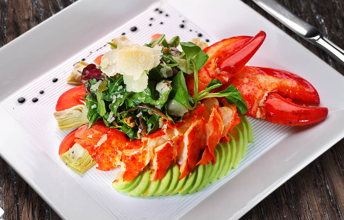 Lobster salad on the white plate on the wooden table.