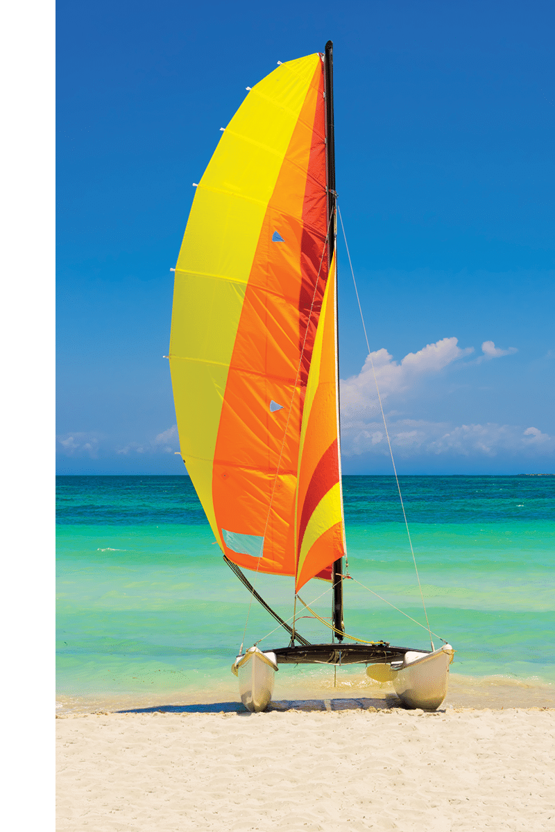 Catamaran with its colorful sails wide open landed on the famous Varadero beach in Cuba