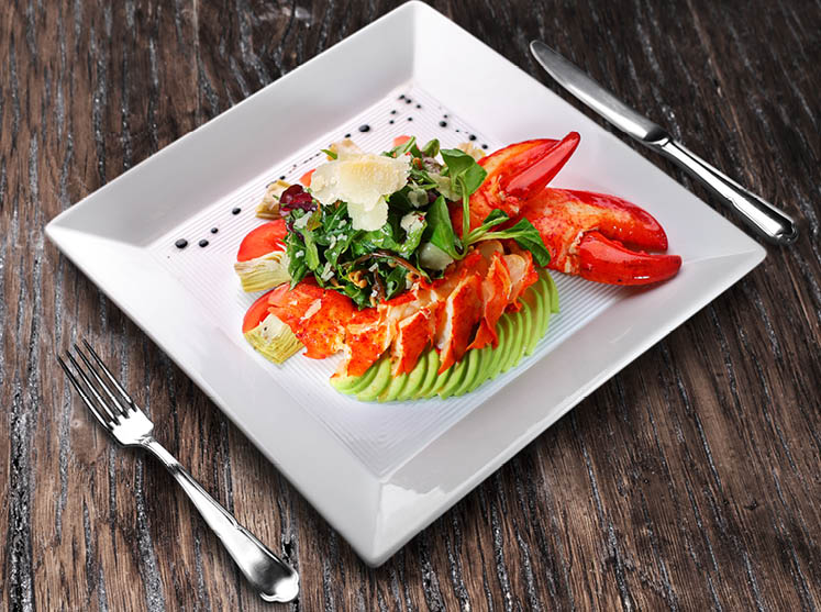 Lobster salad on the white plate on the wooden table.