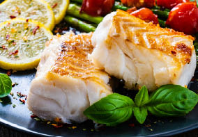 Fish dish - fried cod fillet with asparagus on wooden table 