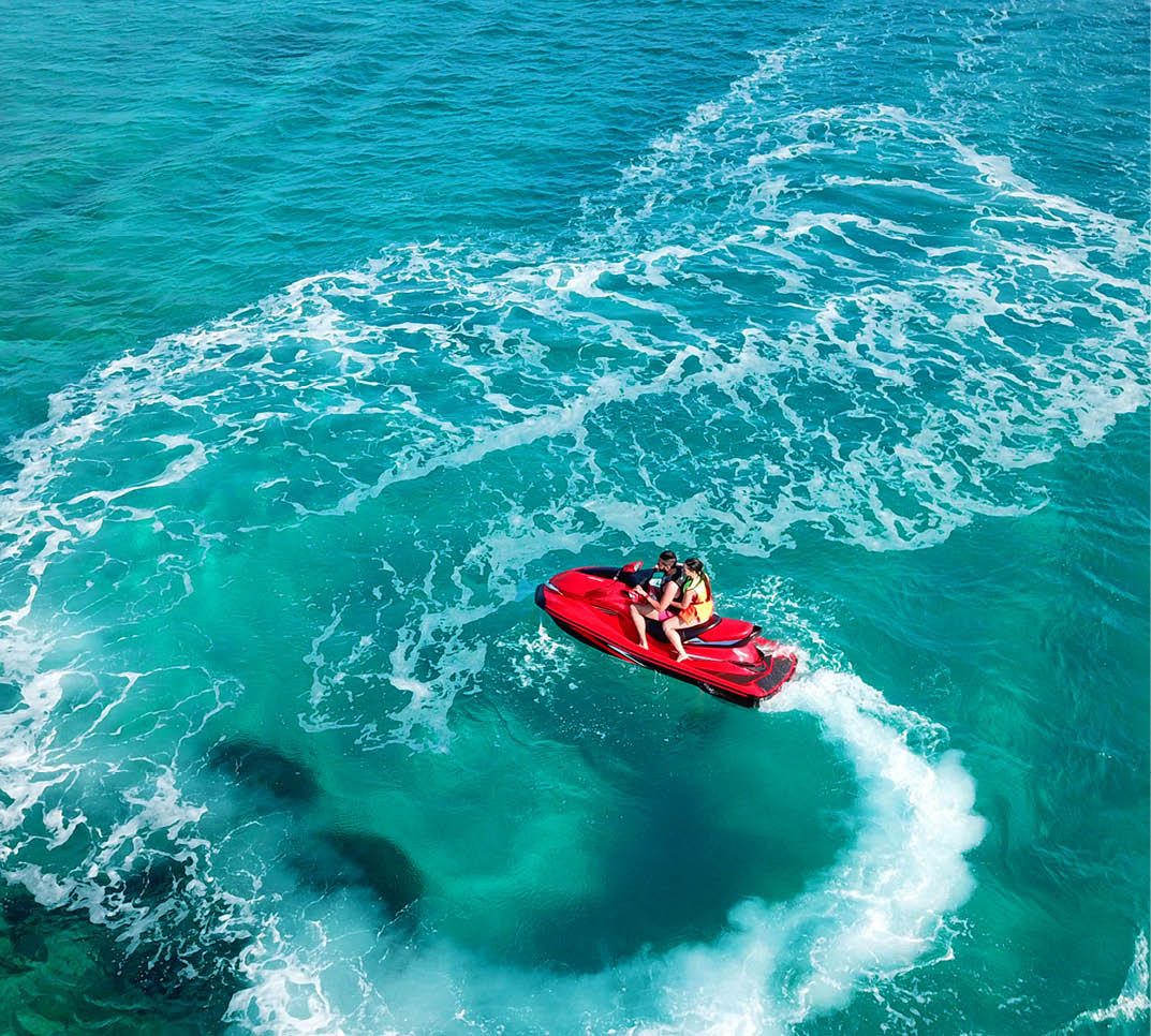 Aerial photo of jet ski with couple cruising in low speed in Caribbean tropical crystal clear waters