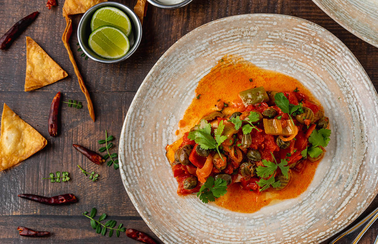 Mexican food huachinango a la veracruzana with sauces on wooden table