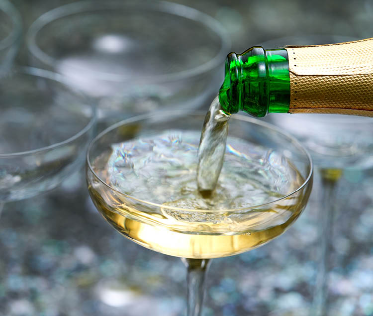 Close up pour champagne in glasses. Sparkling wine pouring into glass. Celebration champagne new years eve party drink.
