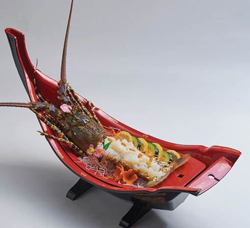 Fresh lobster sashimi served on a boat shaped plate, decorated with delicious seafood dishes.