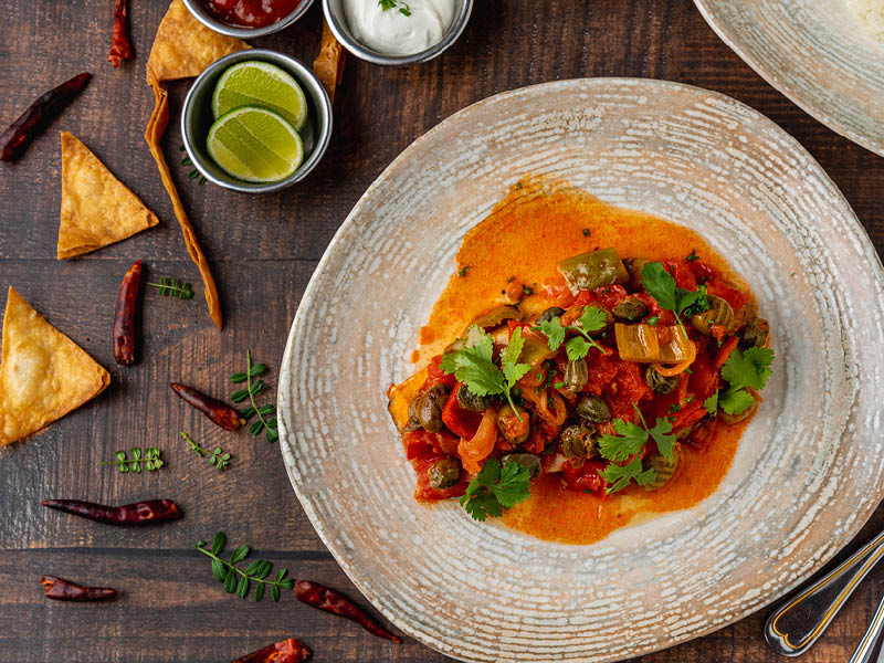 Mexican food huachinango a la veracruzana with sauces on wooden table