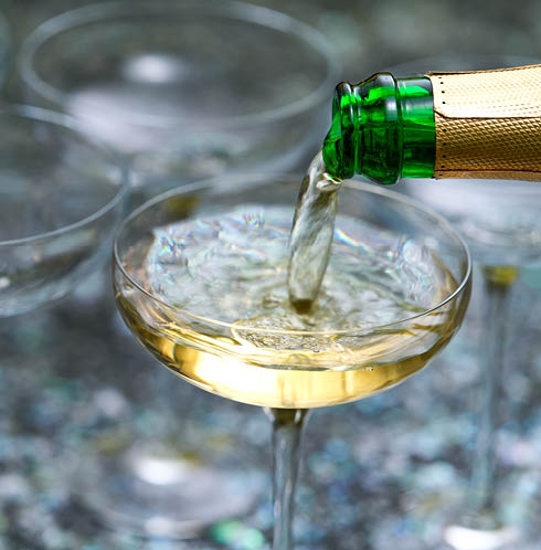 Close up pour champagne in glasses. Sparkling wine pouring into glass. Celebration champagne new years eve party drink.